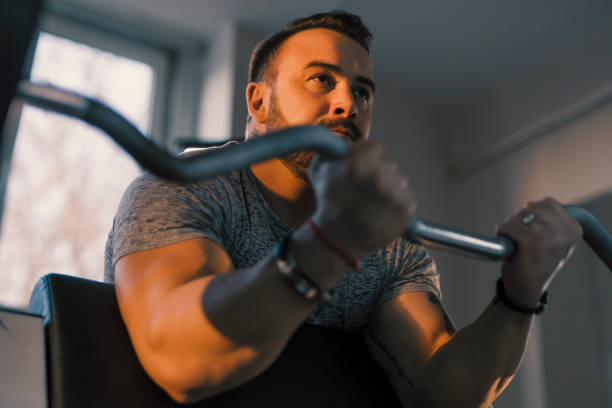 istock Man lifting barbell in a gym on EZ bar preacher curl, biceps exercise 1190032184
