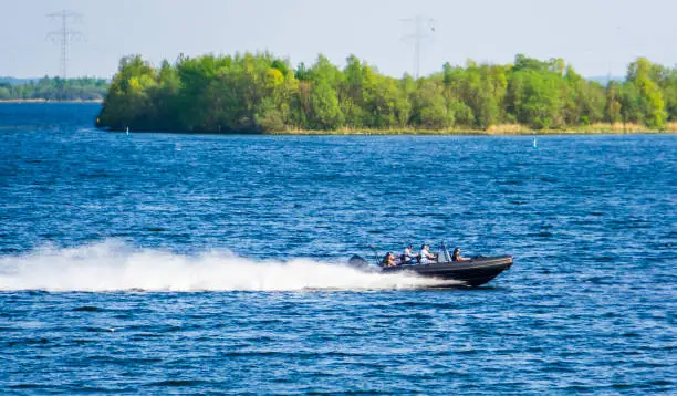 Photo of speedboat with poeple sailing by on the oosterschelde of Tholen, Touristic water sport and transportation, popular city in zeeland, The Netherlands