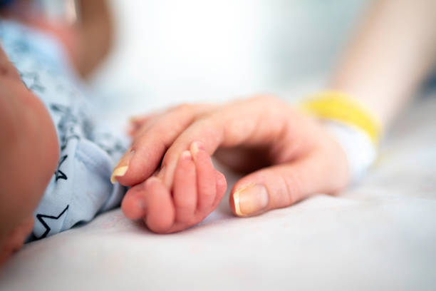 Newborn baby holding mother's finger