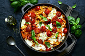 Pasta casserole with tomatoes and mozzarella cheese in a cast iron pan