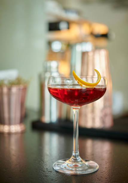 Red clear drink in vintage champagne glass with orange zest decoration on a bar table stock photo