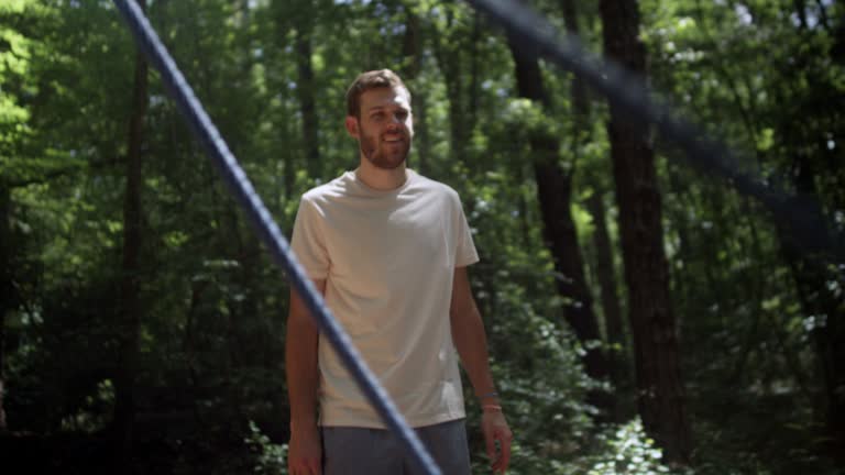 Slow motion low angle shot of a father pushing his cute little blonde daughter on a large playground swing