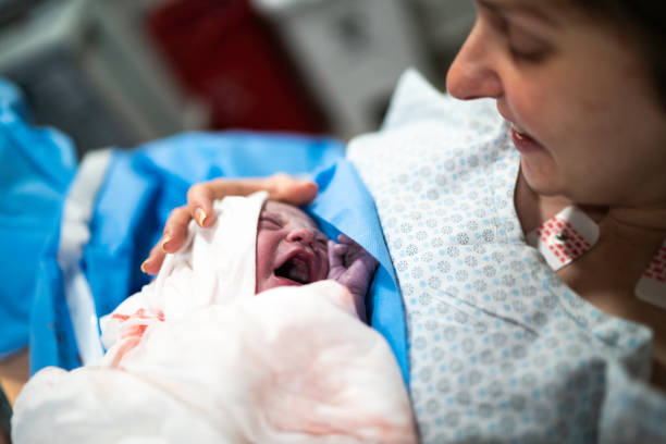 madre sonriente sosteniendo a su bebé en el hospital - common family new togetherness fotografías e imágenes de stock