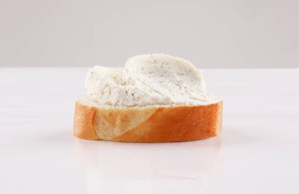 spread cheese with herbs on sliced french baguette canape, spanish tapas low view isolated on white background