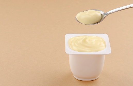 banana and Vanilla pudding white cup plastic with spoon on brown background