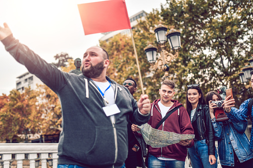 Tour Guide Describing Famous City Location To Group Of Tourists