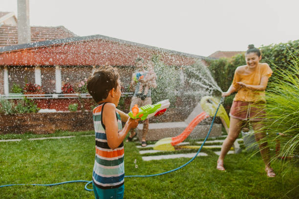 Family water fight in the yard Photo of family water fight in the yard hose photos stock pictures, royalty-free photos & images