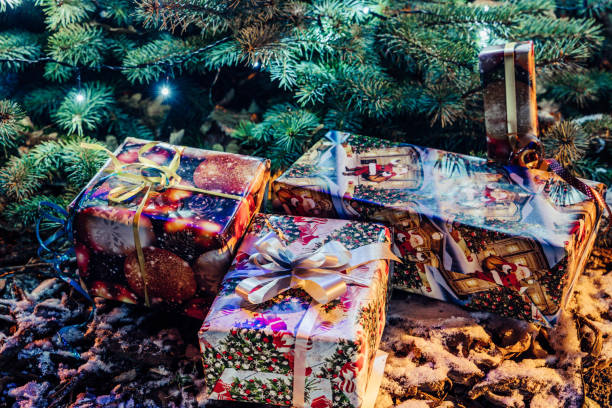 завернутые рождественские подарки под елку с огнями - тема праздника - 2972 стоковые фото и изображения