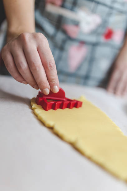 istock Young woman using cookie cutter and cutting out christmas tree shape in dough on table. 1190053599