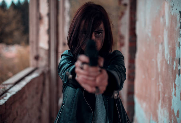 A vertical shot of a mysterious female in a mask holding up a gun