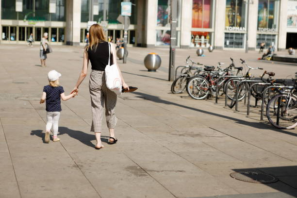 Berlin, Germany - May 19, 2019: In the center of the city of Berlin, on an Alexanderplatz square on a beautiful sunny day, an adult woman with a child is walking with her back turned away. Beside there are bikes based on a rack.