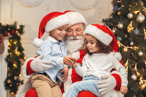 Santa Claus with children indoors holiday concept eating cookies