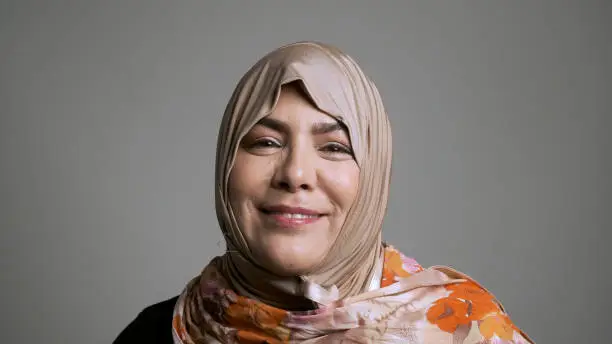 mature muslim woman looking at the camera on gray background