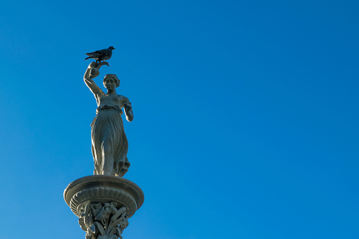 statue of hebe, greek goddess, made in queretaro in the 19th century against a sunny blue sky