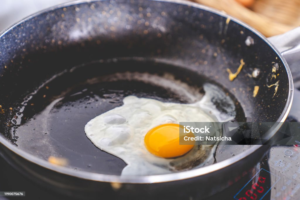 yellow yolk egg, fried egg cooking on flying pan in oil on electric stove, close up selective focus, with copy space Black Color Stock Photo