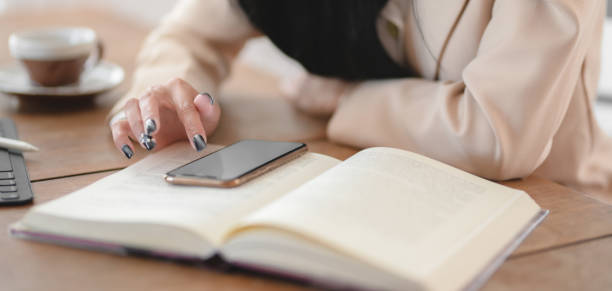 istock Close-up view of businesswoman using her smartphone while working on her project in comfortable workspace 1190075831