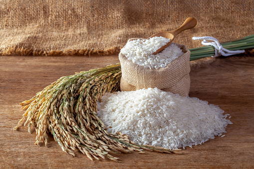 White rice (jasmine rice) in a sack on a wooden background