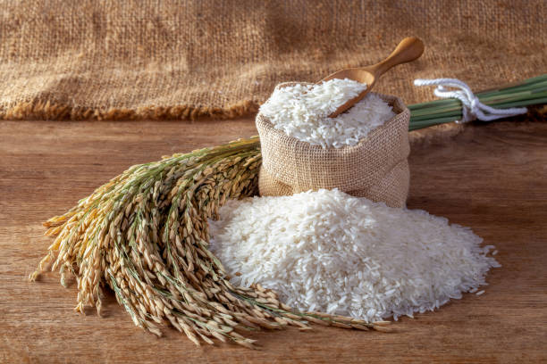 White rice (jasmine rice) in a sack on a wooden background White rice (jasmine rice) in a sack on a wooden background rice food staple stock pictures, royalty-free photos & images