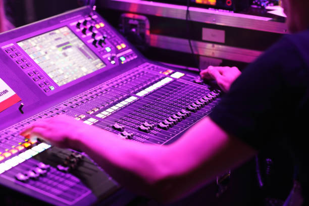 Sound engineer is controlling audio mixer console in live concert event. Selective focus.