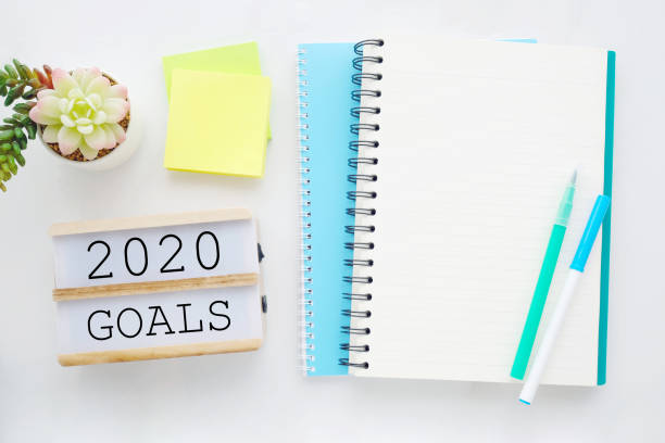 istock 2020 on wood box, blank notebook paper on white marble table background, 2020 new year mock up, template with copy space for text, top view 1190086462