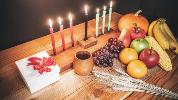 Kwanzaa holiday concept with decorate seven candles red, black and green, gift box, pumpkin,corn and fruit on wooden desk and background. Kwanzaa holiday concept with decorate seven candles red, black and green, gift box, pumpkin,corn and fruit on wooden desk and background. angolan kwanza photos stock pictures, royalty-free photos & images