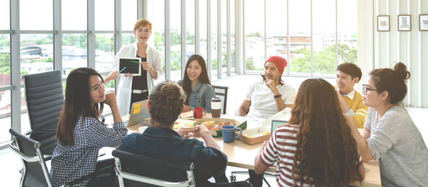 istock Young multiethnic diverse creative asian group talking or brainstorm in office meeting workshop with technology. Happy young student asian or college marketing team spend coffee break time together. 1190089920