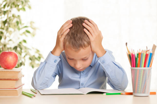 istock Young schoolboy sitting at the table and doing homework 1190090742