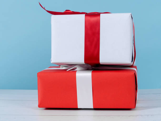 istock Red and white gift boxes on wooden table with blue wall. 1190093285