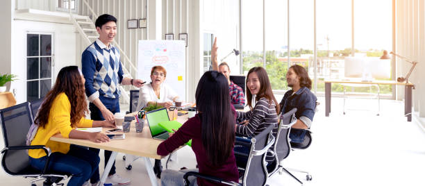 istock Group of young asian creative team talking, smile and laugh brainstorming, sharing or training on meeting or workshop at office. Happy asian workplace sitting attentive together in rear view concept. 1190093290