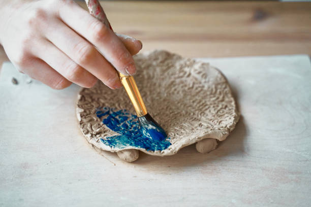 istock Unrecognised Woman making pattern on ceramic plate, hands close-up, focus on palms with paint brush. Creative hobby concept. Earn extra money, side hustle, turning hobbies into cash, passion into job 1190095975