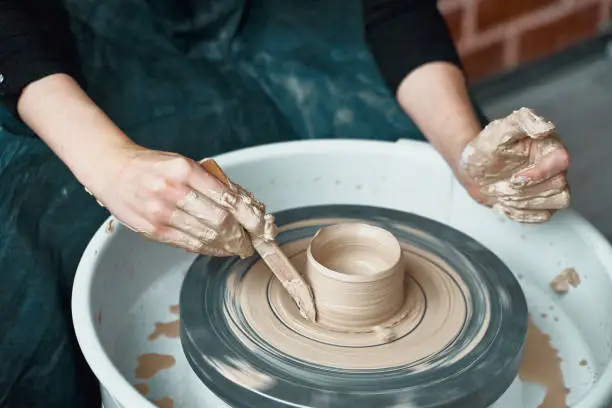 Photo of Woman making ceramic pottery on wheel, hands close-up, creation of ceramic ware. Handwork, craft, manual labor, buisness. Earn extra money, turning hobbies into cash and turning passion into job