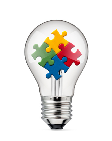Idea and Solution. Light bulb with colored jigsaw puzzle on white background.