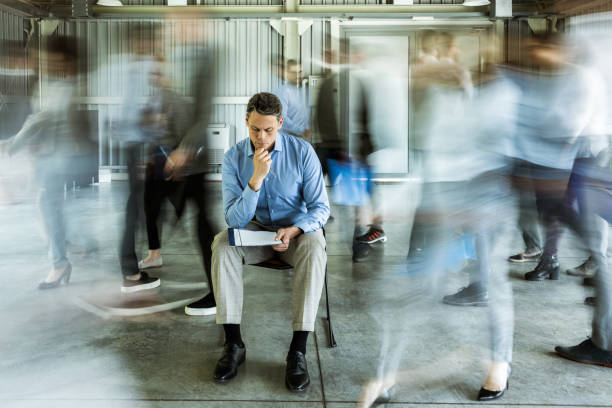 istock Pensive businessman reading reports surrounded by his colleagues in blurred motion. 1190102833