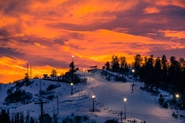 Colorful red sunset over ski slope in Colorado Colorado ski slope with running chairlift at sunset; small figures of people waiting to get up; dramatic sun above the mountain steamboat springs photos stock pictures, royalty-free photos & images