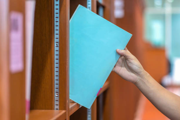 studente scegliere un libro presso scaffali per i dati di ricerca in biblioteca - 15796 foto e immagini stock