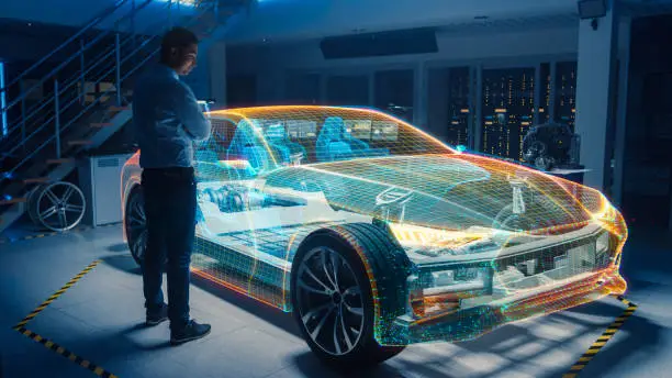 Photo of In Automotive Innovation Facility Automobile Design Engineer Working on 3D Holographic Model Projection of Electric Car. Futuristic Concept of Virtual and Augmented Realty Use.