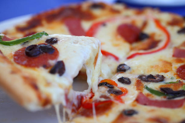 pizza with smoked sausage, mushrooms, black olives, sweet pepper. the piece rises and the cheese stretches. - stringy imagens e fotografias de stock