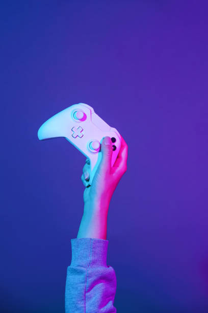 istock Hand with white gamepad on dark violet background. 1190109388