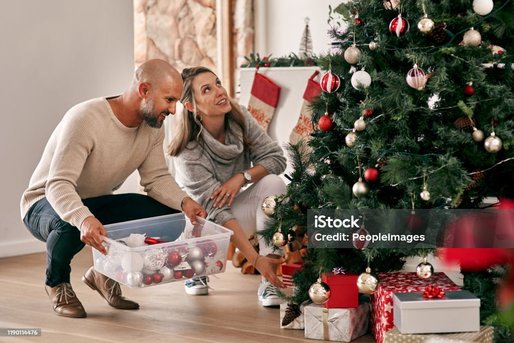 Now to finally put up the star Cropped shot of a cheerful middle aged couple placing decorations on a Christmas tree inside at home during the day Adult Stock Photo