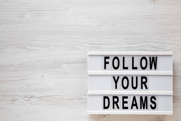 istock 'Follow your dreams' words on a modern board on a white wooden surface, top view. Overhead, from above, flat lay. Space for text. 1190114516