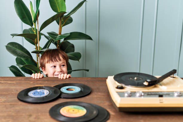 niño lindo escuchando música en la mesa - disco audio analógico fotografías e imágenes de stock