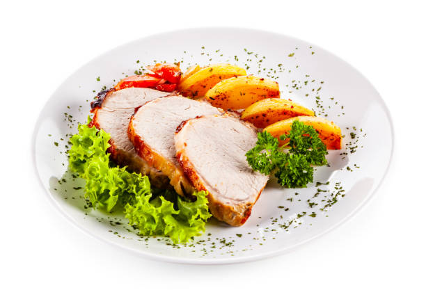 istock Roast pork, baked potatoes and vegetable salad on white backgound 1190115719