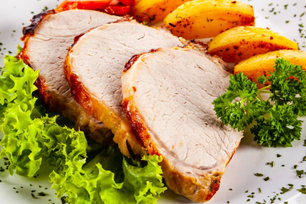 istock Roast pork, baked potatoes and vegetable salad on white backgound 1190115803