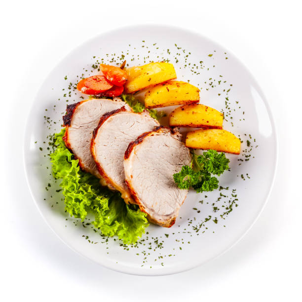 istock Roast pork, baked potatoes and vegetable salad on white backgound 1190115877