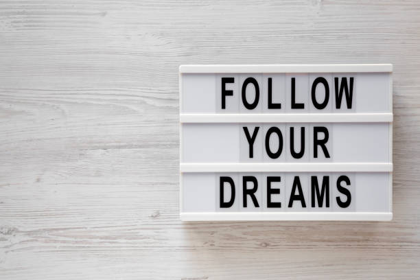istock 'Follow your dreams' words on a modern board on a white wooden surface, top view. Overhead, from above, flat lay. Copy space. 1190115972