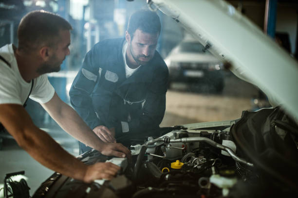 istock Worried auto mechanics working on car engine in a workshop. 1190117911
