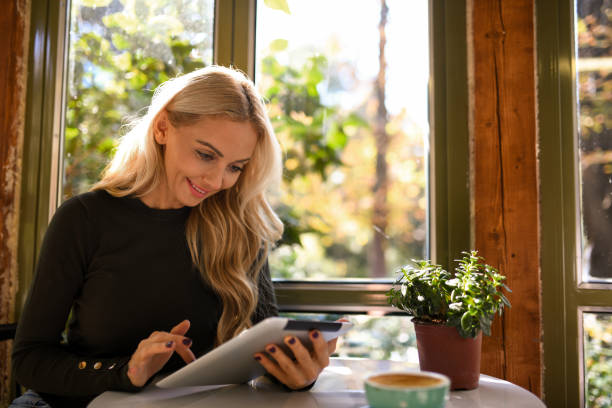 istock Attractive blond woman using her tablet by the window in coffee shop. 1190120399