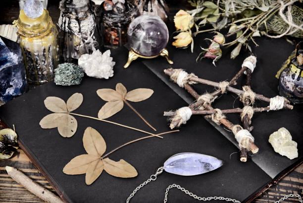 istock Creepy still life with open book, pentagram, four-lead clover and crystals on witch table. 1190122204