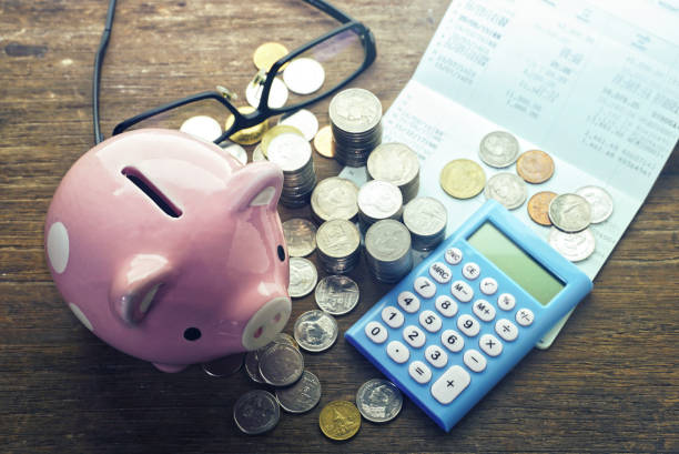 istock Top angle view coins stack and calculator and piggy save and banking passbook on wood table 1190124567