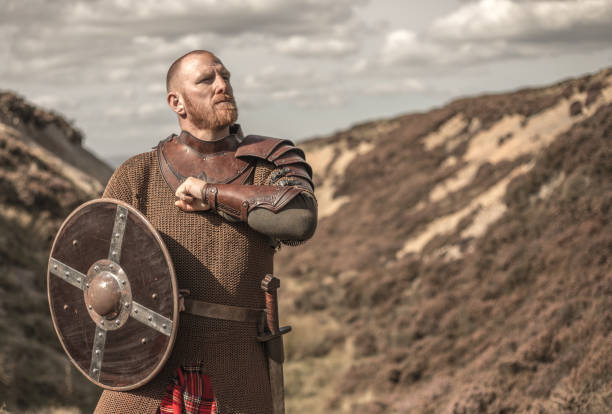 Scottish warrior wearing a kilt A lone redhead individual Scottish viking sword wielding warrior man wearing a kilt on highland moors armory photos stock pictures, royalty-free photos & images